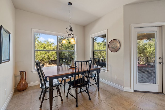 dining space with a wealth of natural light, a notable chandelier, and light tile patterned flooring