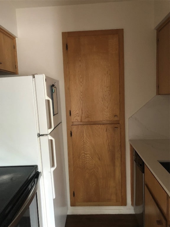 kitchen with dark wood-type flooring, white refrigerator, and stainless steel dishwasher