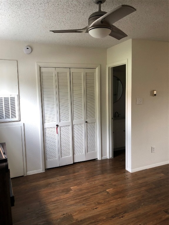 unfurnished bedroom with a textured ceiling, ceiling fan, a closet, and dark hardwood / wood-style flooring