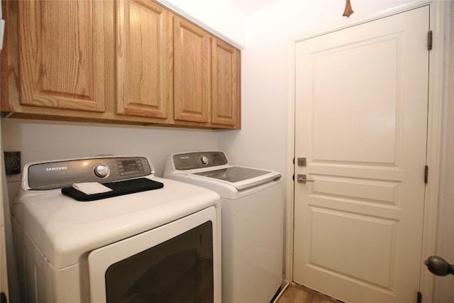 laundry room featuring cabinets, hardwood / wood-style floors, and washing machine and clothes dryer