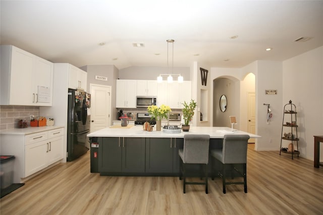 kitchen with tasteful backsplash, white cabinets, and black refrigerator