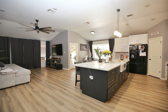 kitchen featuring light hardwood / wood-style flooring, white cabinets, sink, and black refrigerator