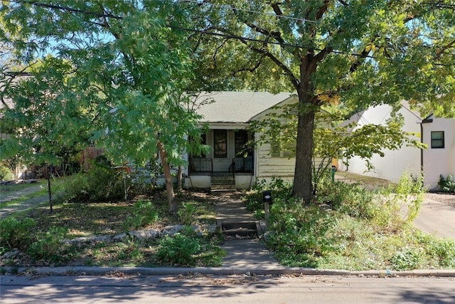 view of property hidden behind natural elements featuring covered porch