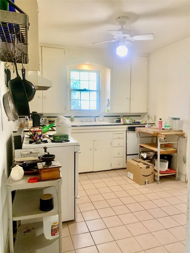 kitchen with light tile patterned floors, dishwasher, ceiling fan, white cabinetry, and stove