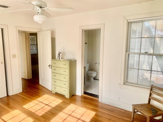 bedroom with ceiling fan, ensuite bath, and light hardwood / wood-style floors