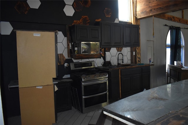 kitchen featuring stone counters, sink, stainless steel appliances, and tasteful backsplash