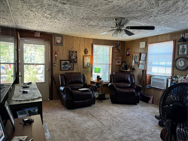 living room with ceiling fan, cooling unit, wooden walls, and carpet flooring