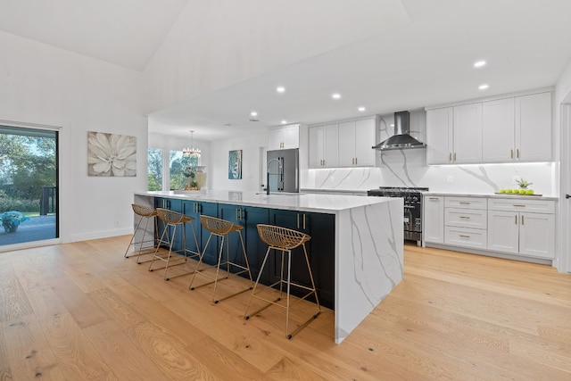 kitchen with white cabinetry, sink, a large island, wall chimney range hood, and high end appliances