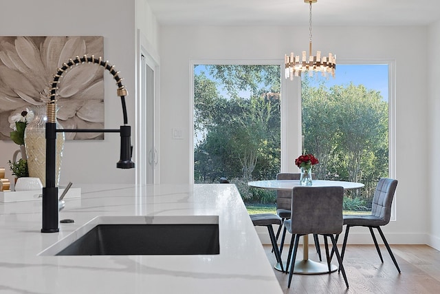 dining space with light wood-type flooring, sink, and a chandelier