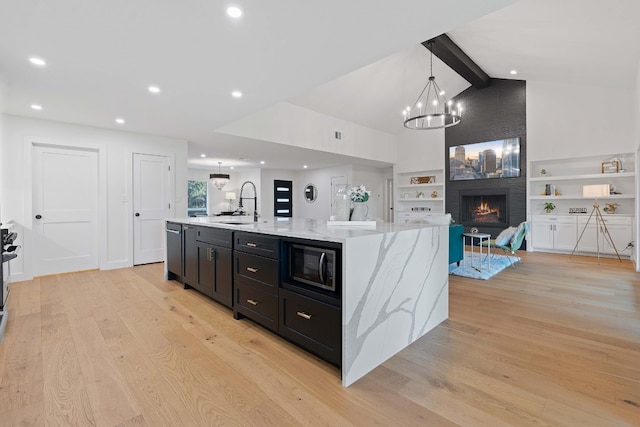 kitchen featuring built in microwave, a spacious island, built in features, a fireplace, and vaulted ceiling with beams