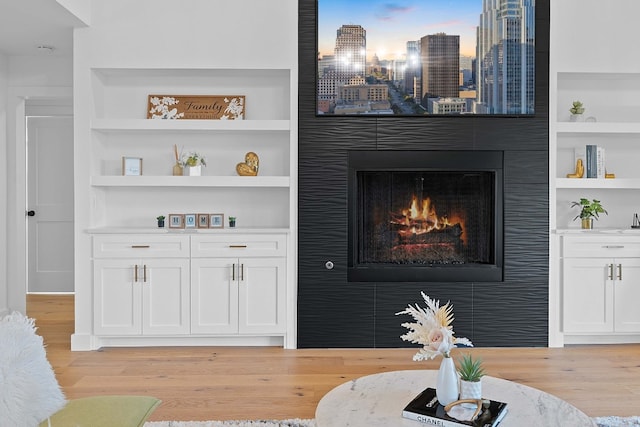 living room with built in features and light hardwood / wood-style floors