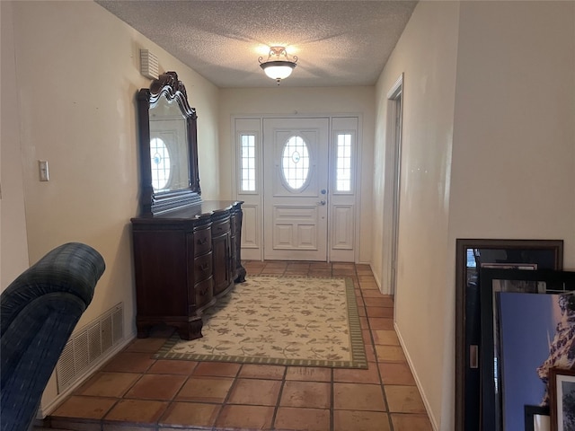 entrance foyer featuring a healthy amount of sunlight, a textured ceiling, and light tile patterned flooring