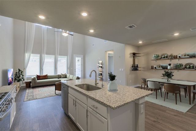 kitchen featuring stainless steel appliances, a kitchen island with sink, dark wood-type flooring, sink, and white cabinets