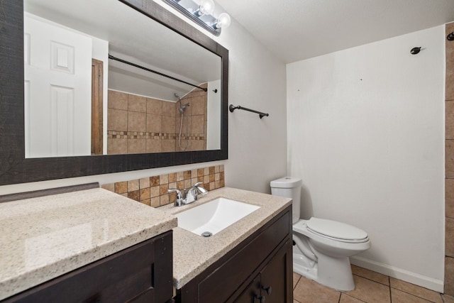 bathroom with a tile shower, backsplash, vanity, toilet, and tile patterned floors