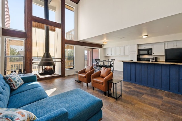 living room featuring a wood stove and a towering ceiling