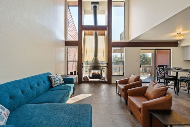 living area featuring a wood stove, tile patterned flooring, and a towering ceiling