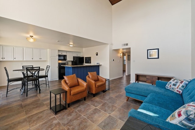 living room featuring a high ceiling, visible vents, and baseboards