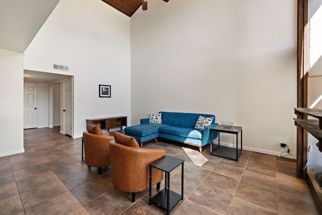 living area featuring stone finish flooring, high vaulted ceiling, baseboards, and visible vents