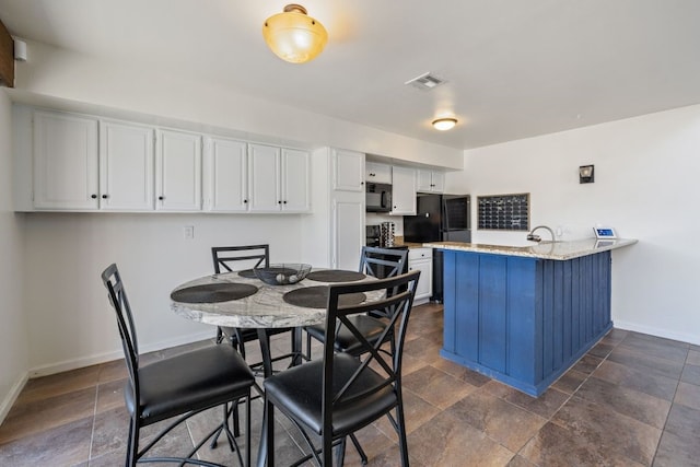 kitchen with black appliances, kitchen peninsula, and white cabinets