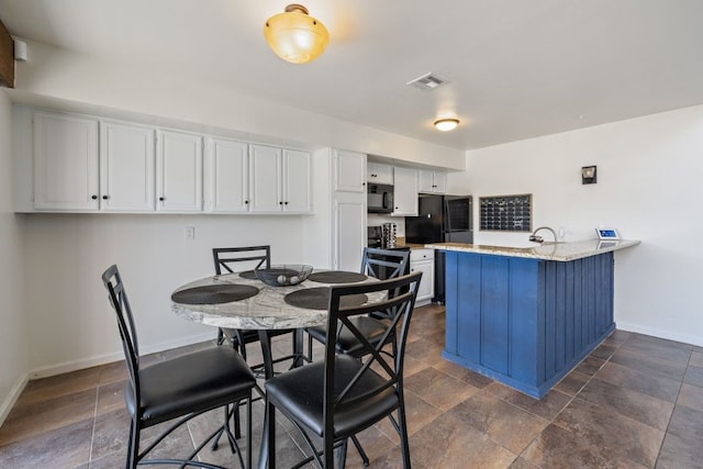 dining room featuring baseboards, visible vents, and stone finish floor
