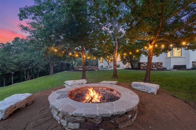 patio terrace at dusk featuring a yard and a fire pit