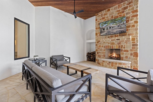 living room featuring ceiling fan, wood ceiling, and an outdoor stone fireplace