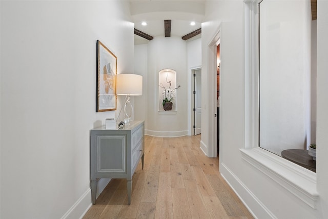 hallway with light hardwood / wood-style floors and beam ceiling