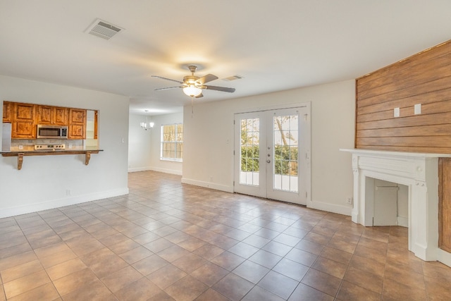 unfurnished living room with french doors, light tile patterned flooring, and ceiling fan with notable chandelier