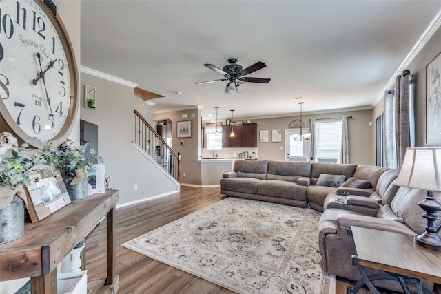 living room with ceiling fan with notable chandelier, crown molding, and hardwood / wood-style floors