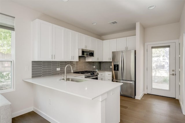 909 Capitol Ct Unit 2, Austin, TX 78756 - kitchen with appliances with stainless steel finishes, light countertops, backsplash, light wood-style flooring, and a peninsula