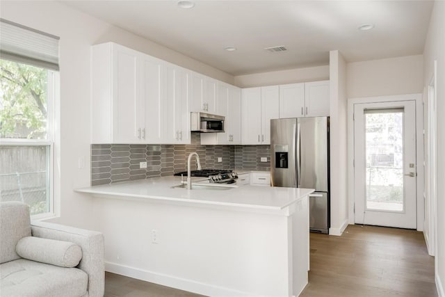 909 Capitol Ct Unit 2, Austin, TX 78756 - kitchen with appliances with stainless steel finishes, light countertops, a peninsula, tasteful backsplash, and white cabinetry