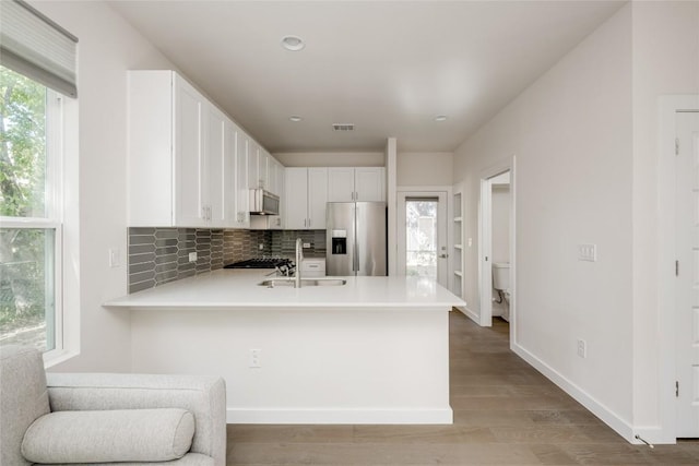 909 Capitol Ct Unit 2, Austin, TX 78756 - kitchen featuring stainless steel refrigerator with ice dispenser, light countertops, tasteful backsplash, light wood-style floors, and a peninsula