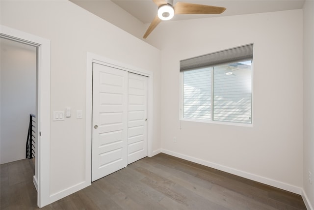 unfurnished bedroom with ceiling fan, a closet, vaulted ceiling, and wood-type flooring