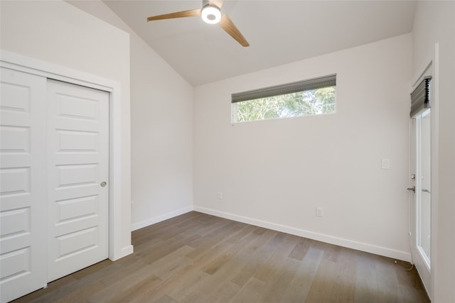 unfurnished bedroom featuring lofted ceiling, a closet, light wood-type flooring, and ceiling fan