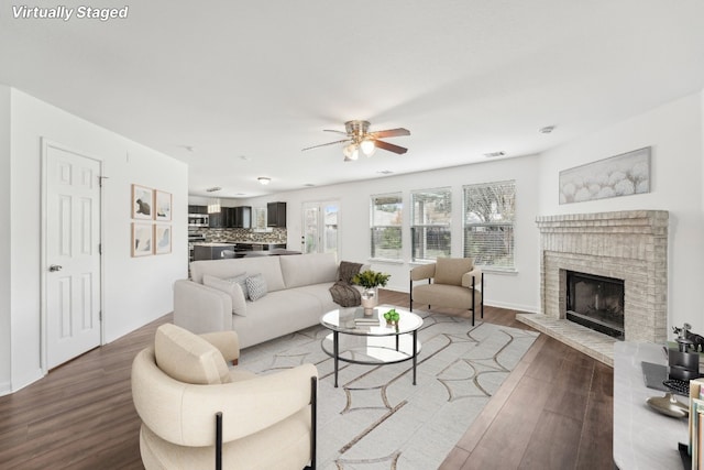 living room with a fireplace, wood-type flooring, and ceiling fan