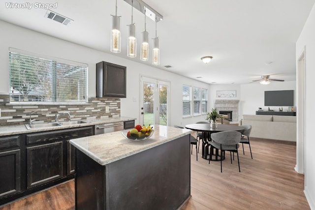 kitchen featuring decorative light fixtures, a center island, sink, and a wealth of natural light