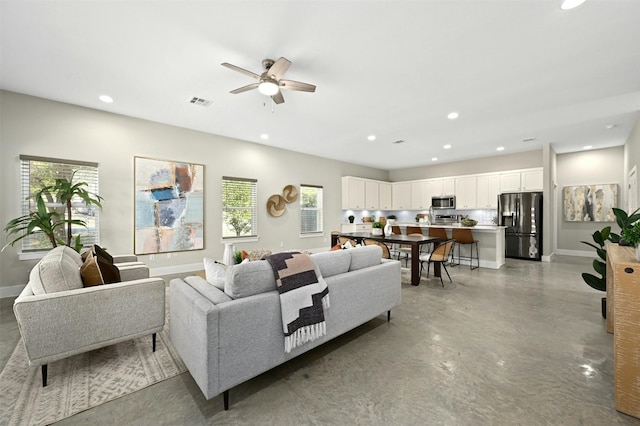 living room featuring ceiling fan and a healthy amount of sunlight