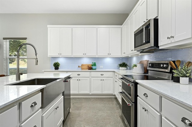 kitchen with white cabinetry, appliances with stainless steel finishes, sink, and light stone counters