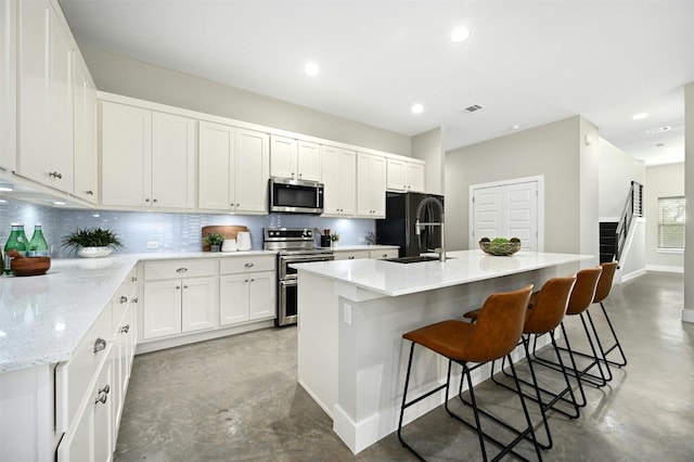 kitchen with a breakfast bar, white cabinetry, sink, a kitchen island with sink, and stainless steel appliances