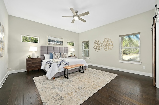 bedroom with dark wood-type flooring, ceiling fan, and a barn door