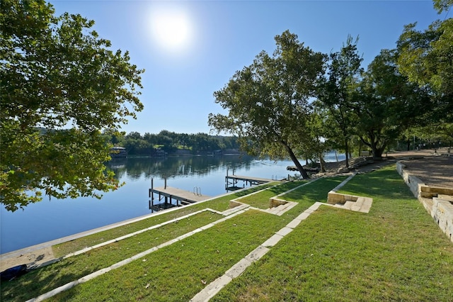 view of dock featuring a lawn and a water view