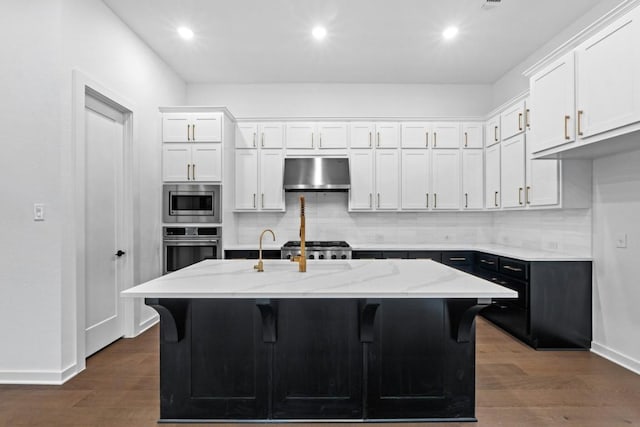 kitchen featuring a kitchen island with sink, appliances with stainless steel finishes, range hood, dark hardwood / wood-style flooring, and white cabinetry