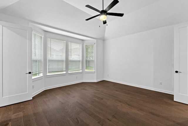 empty room with ceiling fan, dark hardwood / wood-style flooring, a wealth of natural light, and vaulted ceiling