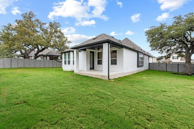 back of property with ceiling fan, a yard, and a patio