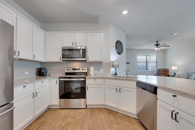 kitchen with white cabinets, appliances with stainless steel finishes, sink, and light hardwood / wood-style flooring