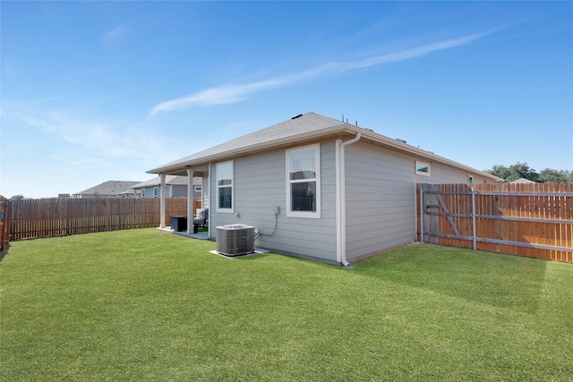 rear view of property with central air condition unit and a lawn