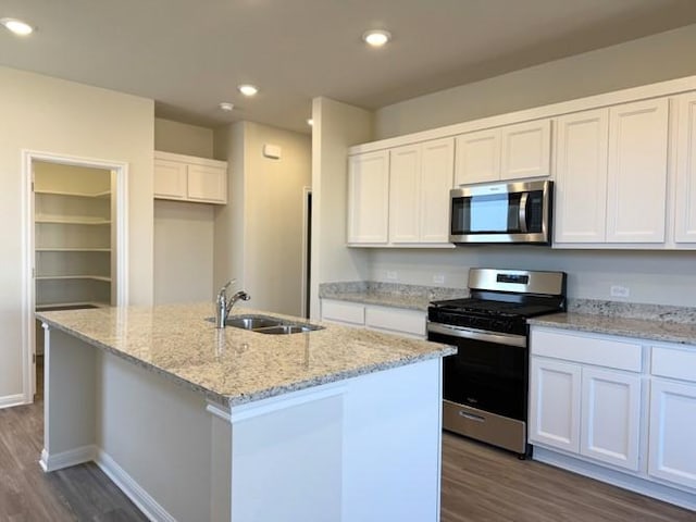 239 Hidalgo Ln, Elgin, TX 78621 - kitchen with stainless steel appliances, a sink, dark wood-type flooring, white cabinetry, and an island with sink