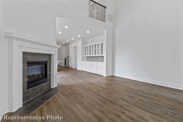 unfurnished living room with a tiled fireplace and dark hardwood / wood-style flooring