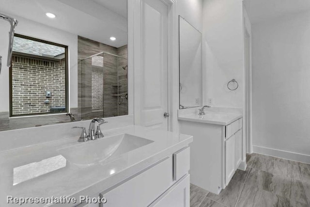 bathroom featuring a shower with shower door and vanity