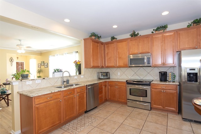 kitchen with sink, decorative backsplash, light tile patterned floors, light stone countertops, and appliances with stainless steel finishes